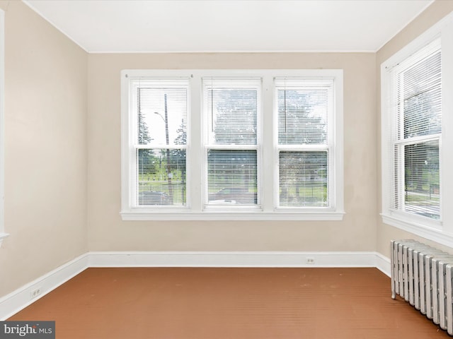 unfurnished room with carpet floors, baseboards, plenty of natural light, and radiator heating unit