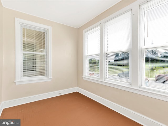 unfurnished room featuring a healthy amount of sunlight, baseboards, and dark colored carpet