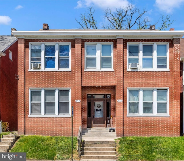 townhome / multi-family property with cooling unit and brick siding