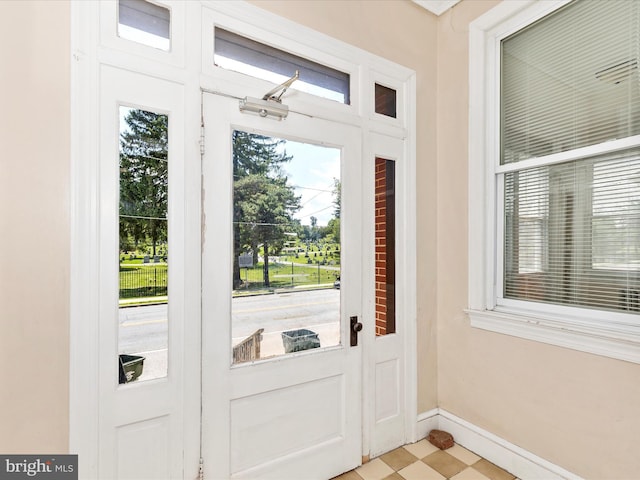 doorway featuring baseboards and light floors