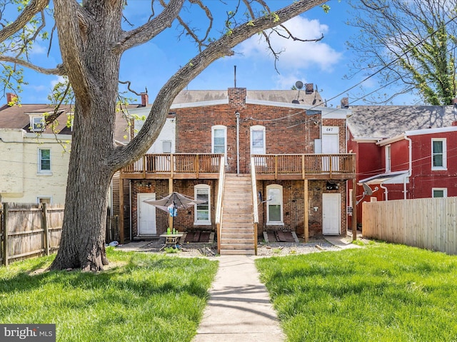 back of house with stairway, brick siding, fence, and a lawn