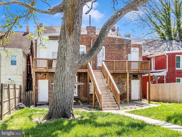 rear view of house featuring stairway, brick siding, fence, and a deck