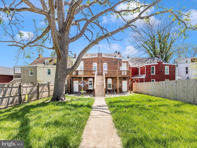 rear view of house with brick siding, a lawn, and fence private yard