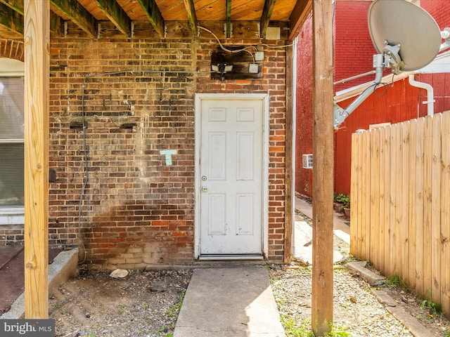 property entrance with brick siding and fence