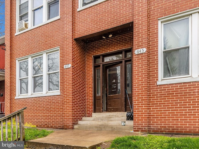 view of exterior entry with brick siding and cooling unit