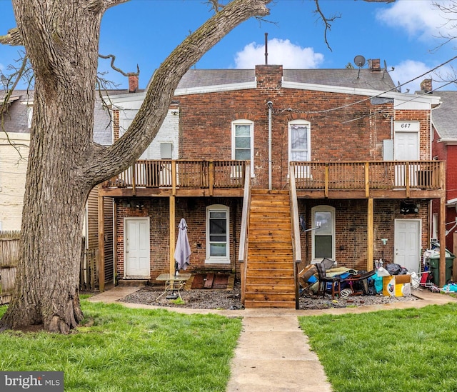rear view of house with a wooden deck, stairs, a lawn, and brick siding