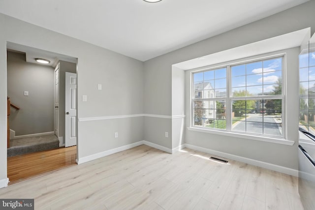empty room with light wood-style floors, baseboards, and stairway