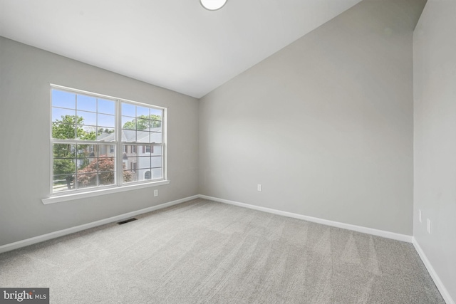 carpeted empty room with baseboards and lofted ceiling