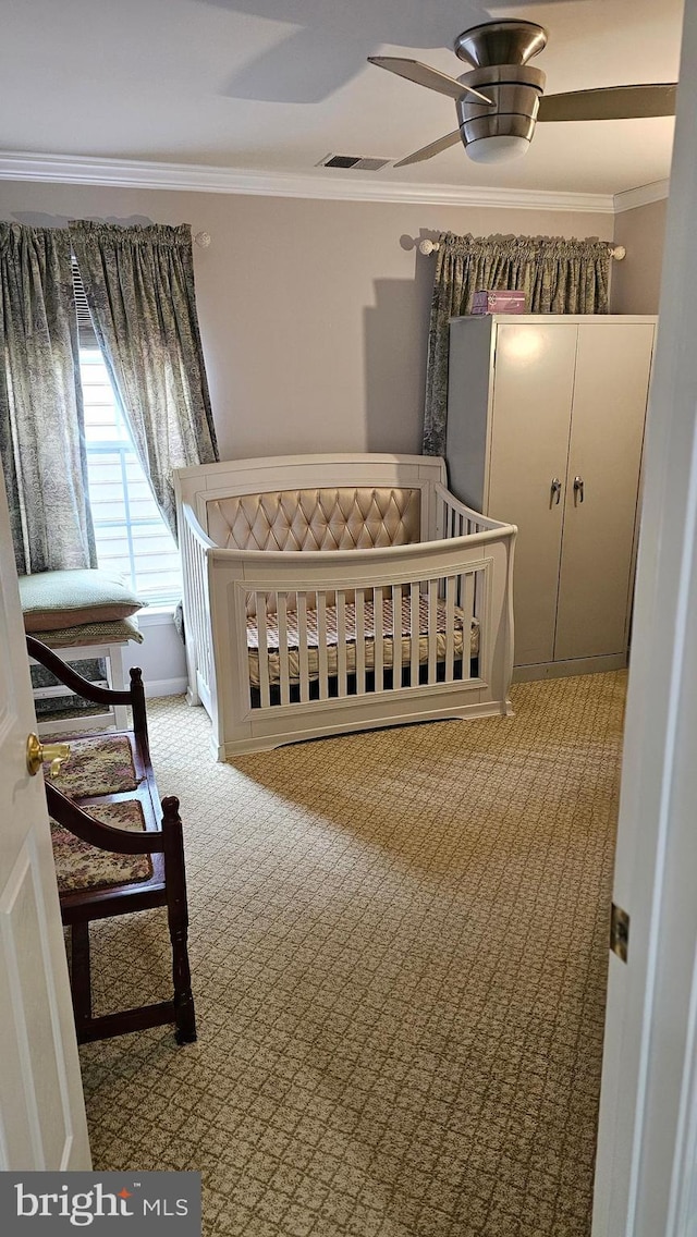 bedroom with crown molding, a nursery area, visible vents, and carpet floors