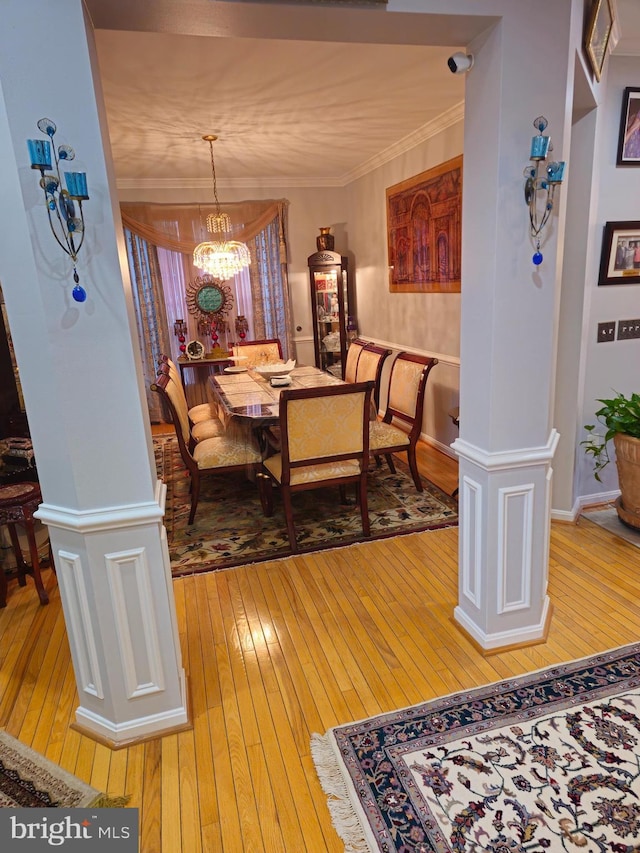 dining space with crown molding, light wood-style flooring, a notable chandelier, and baseboards