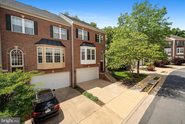 multi unit property with brick siding, driveway, and a garage