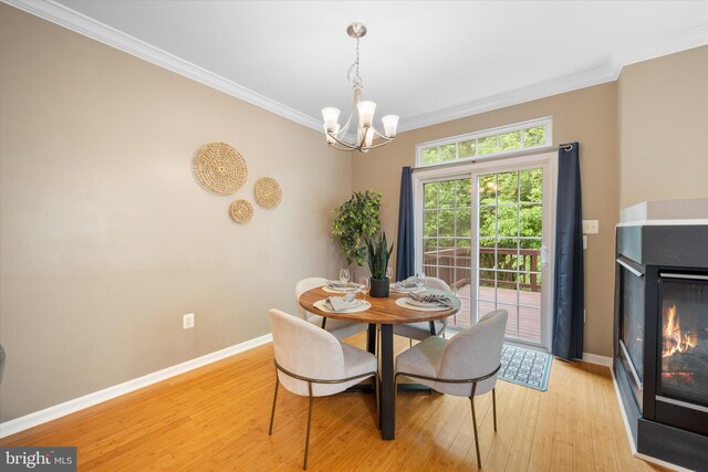 dining room featuring ornamental molding, a chandelier, light wood-style floors, baseboards, and a multi sided fireplace