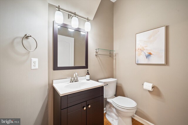 bathroom with toilet, baseboards, vanity, and wood finished floors