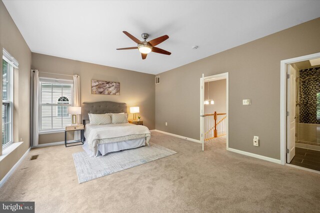 bedroom with light carpet, baseboards, ensuite bath, and a ceiling fan