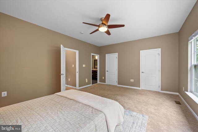 bedroom featuring baseboards, carpet floors, ensuite bath, and a ceiling fan