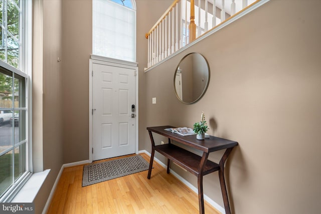 entryway featuring light wood-style floors, healthy amount of natural light, a high ceiling, and baseboards