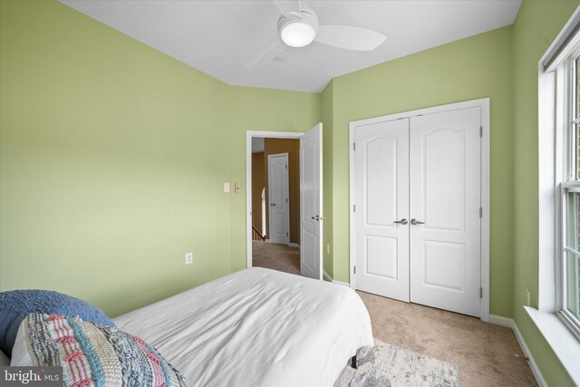 carpeted bedroom with a closet, ceiling fan, and baseboards