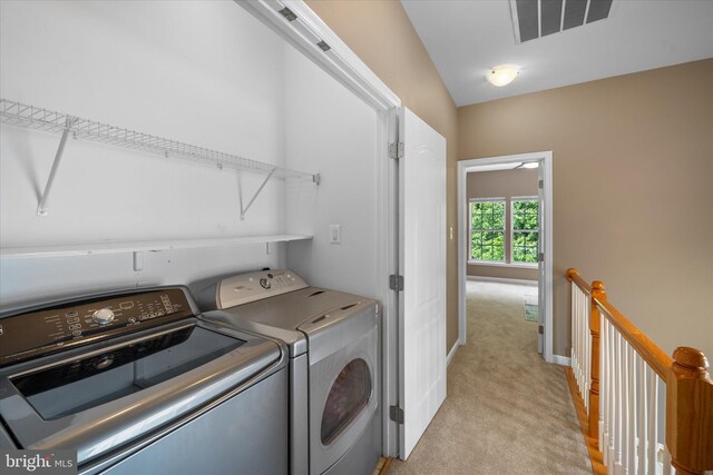 clothes washing area featuring light carpet, separate washer and dryer, and baseboards