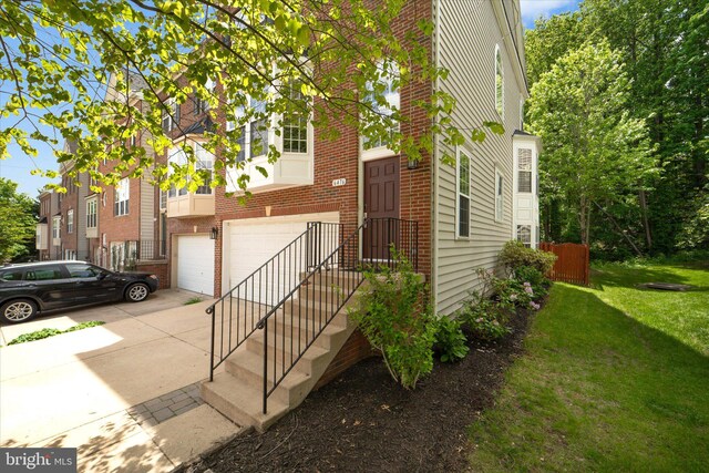 view of front of property featuring brick siding, an attached garage, concrete driveway, and a front lawn