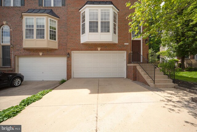 multi unit property with driveway, brick siding, and a garage
