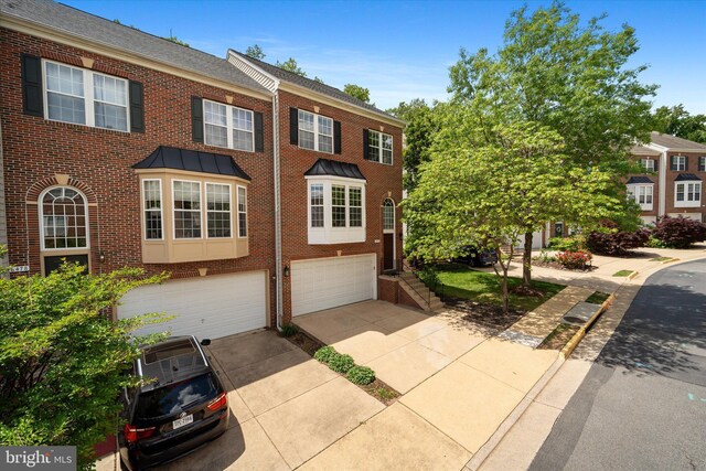 multi unit property featuring brick siding, a garage, and concrete driveway