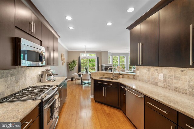 kitchen featuring appliances with stainless steel finishes, a sink, ornamental molding, recessed lighting, and light wood-style floors
