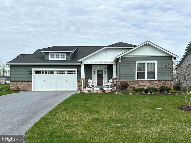 craftsman-style house with a garage, driveway, stone siding, and a front lawn