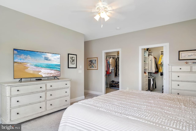 bedroom with a walk in closet, baseboards, and light colored carpet