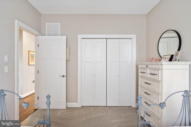 bedroom featuring light colored carpet, baseboards, visible vents, and a closet