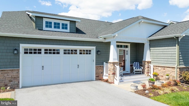 craftsman-style house featuring stone siding, driveway, covered porch, and roof with shingles