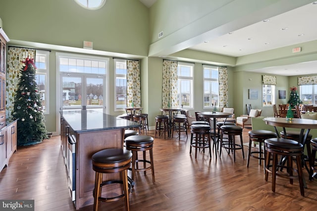 dining space featuring visible vents, a high ceiling, and dark wood-type flooring