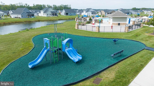 community playground featuring a yard, a residential view, a water view, and fence