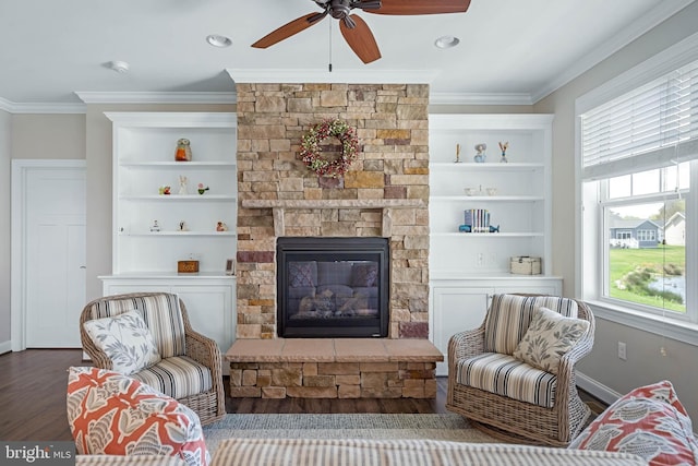 living room featuring a ceiling fan, wood finished floors, a fireplace, and crown molding