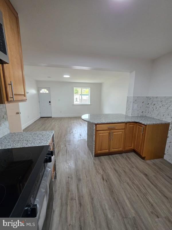 607 N 8th St, Pottsville, PA 17901 - kitchen with a peninsula, light wood-style flooring, stainless steel range with electric stovetop, and light stone counters