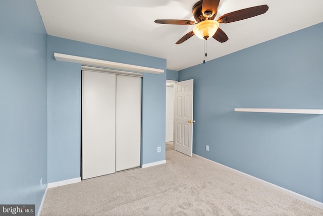 unfurnished bedroom with a closet, baseboards, a ceiling fan, and carpet floors