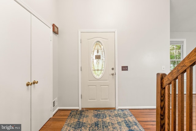 foyer with wood finished floors, baseboards, and visible vents