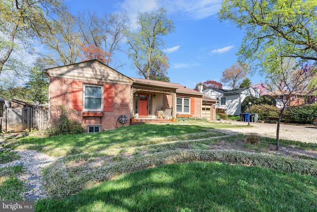 view of front of property with covered porch, an attached garage, fence, a front yard, and brick siding