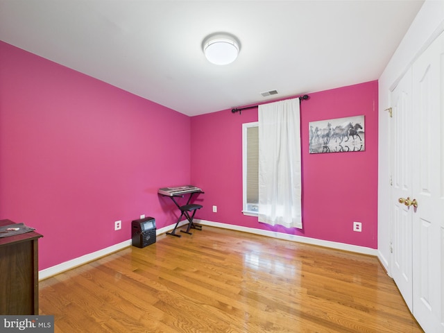 unfurnished bedroom with wood finished floors, baseboards, and a closet