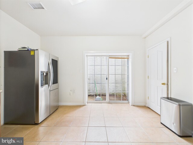 kitchen with stainless steel fridge, light tile patterned flooring, and baseboards