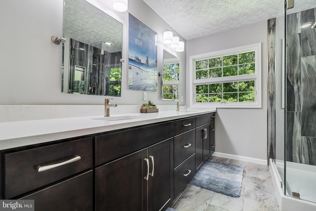 full bath with double vanity, a sink, a textured ceiling, and a stall shower