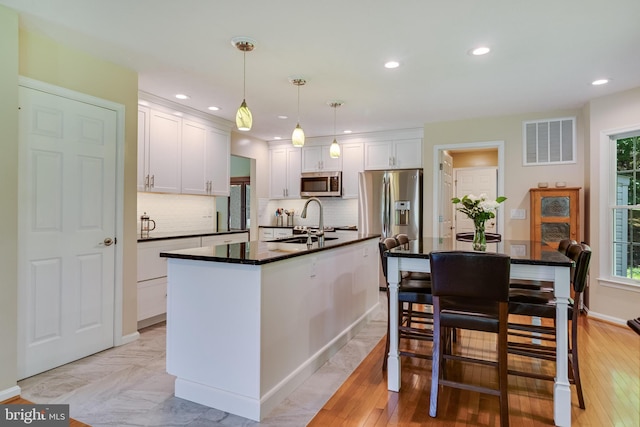kitchen with dark countertops, appliances with stainless steel finishes, white cabinets, and visible vents
