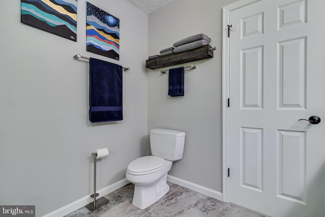 bathroom featuring baseboards and toilet