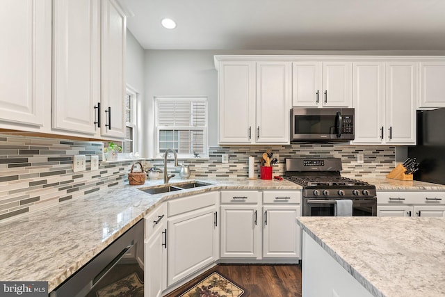 kitchen featuring white cabinets, dark wood-style flooring, appliances with stainless steel finishes, a sink, and decorative backsplash