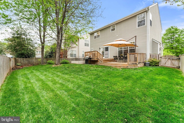 back of property featuring a yard, a gate, a wooden deck, and a fenced backyard