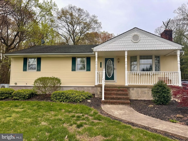 view of front facade with covered porch, a chimney, and a front yard