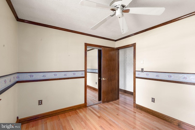 spare room with crown molding, a ceiling fan, baseboards, and light wood-style floors