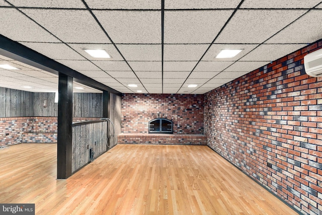 unfurnished living room featuring brick wall, wood finished floors, and a fireplace