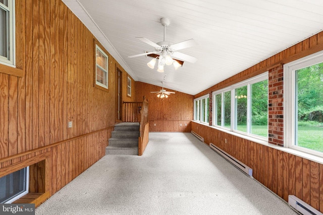 unfurnished sunroom featuring wooden walls, a healthy amount of sunlight, and baseboard heating