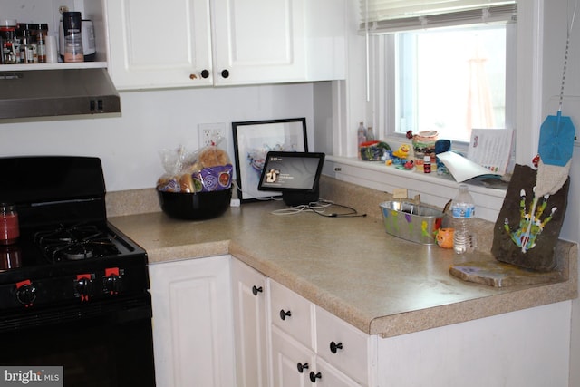 kitchen featuring white cabinets, under cabinet range hood, light countertops, and gas stove