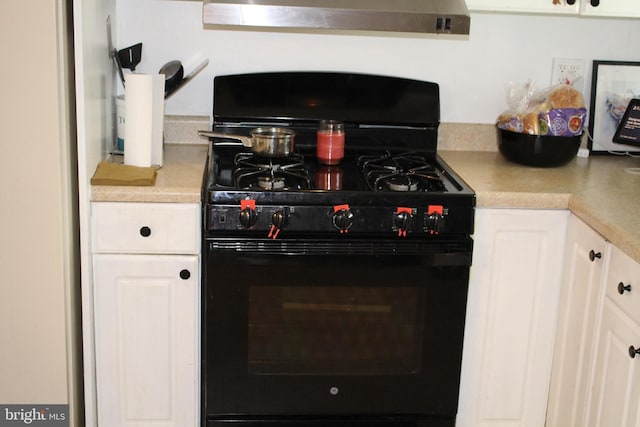 interior details featuring range hood, light countertops, white cabinetry, and gas stove